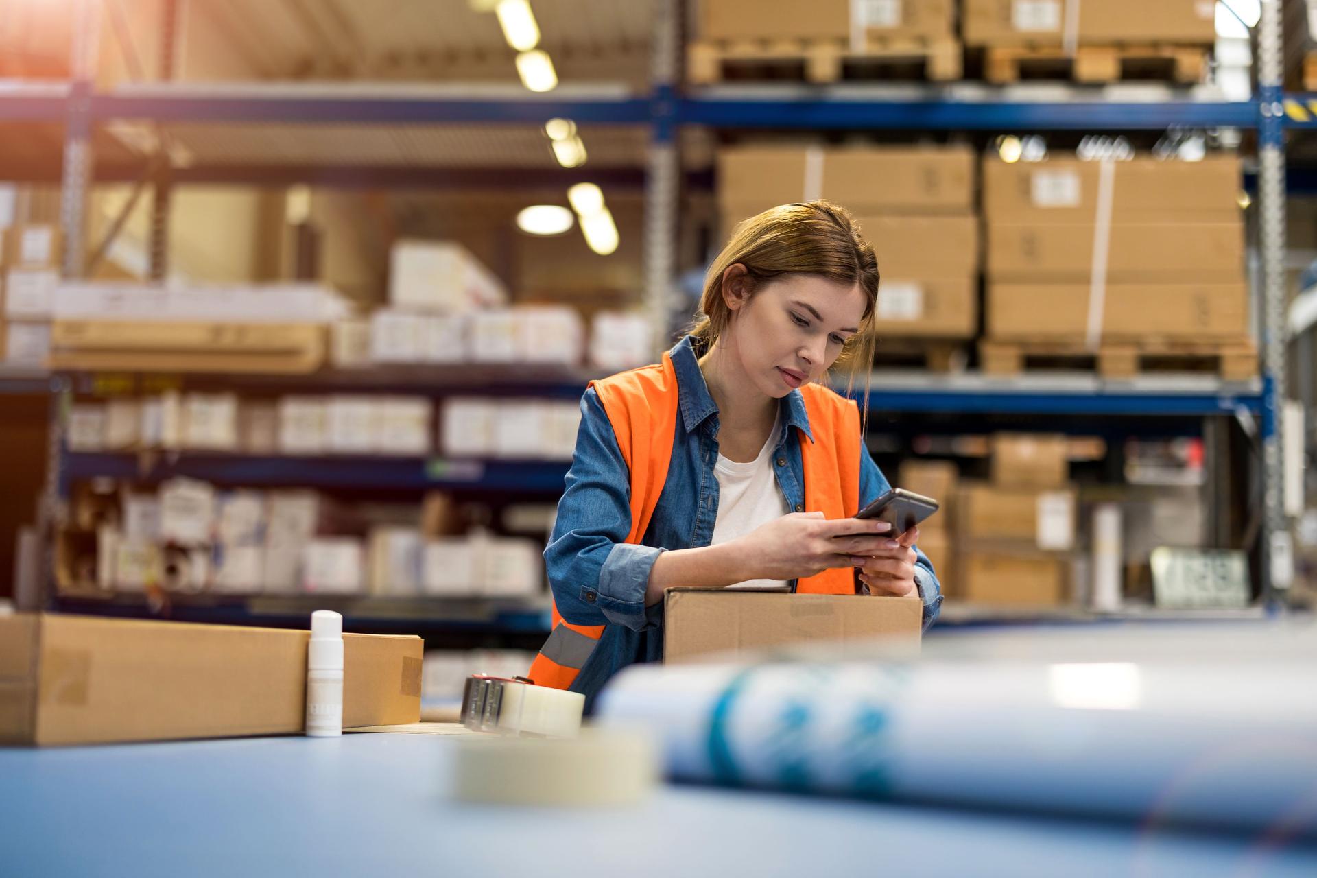 Female warehouse worker using mobile phone